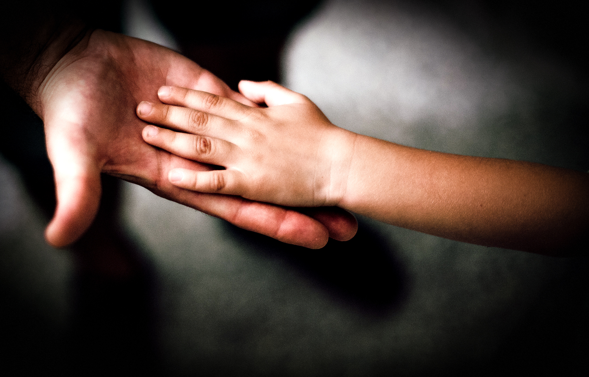 Barn som lägger sin hand i vuxens hand. 