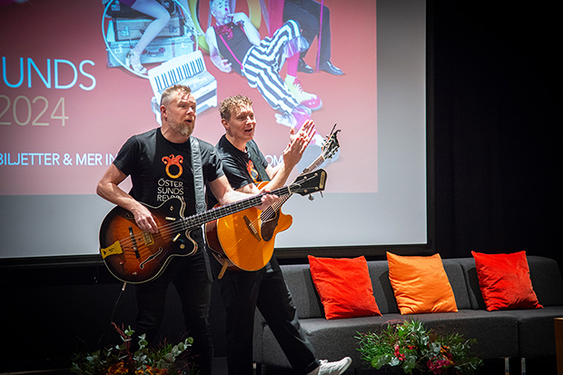 Två personer spelar gitarr på scen.