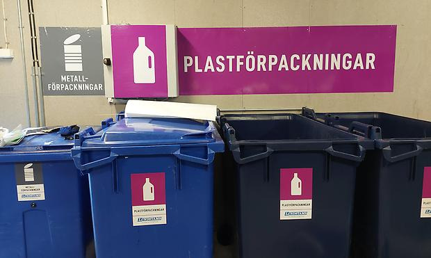 Blå och gröna kärl märkta med symboler för förpackningar av metall och plast