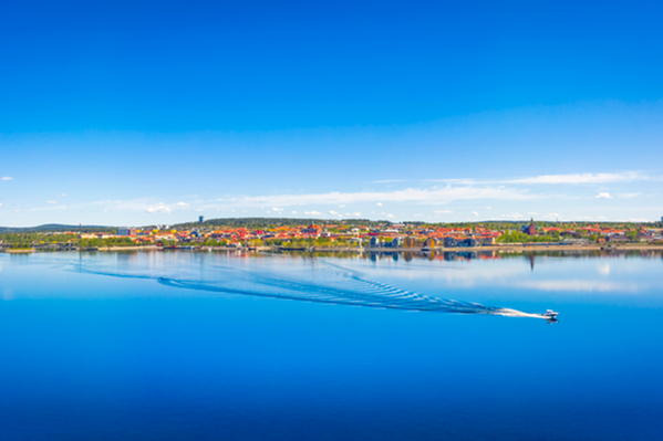 Bild på Storsjön med vy över Östersund. En båt åker över den blanka vattenytan. 