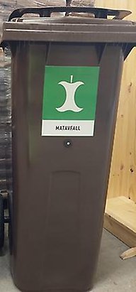 Brunt matavfallskärl med en grön dekal och en vit äppelskruttssymbol