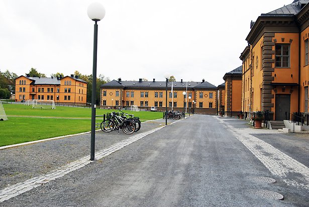 Stenbyggnad i gul puts runt en grön gräsmatta...