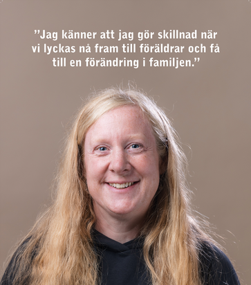 En kvinna med en blå arbetströja och namnbricka på bröstet.