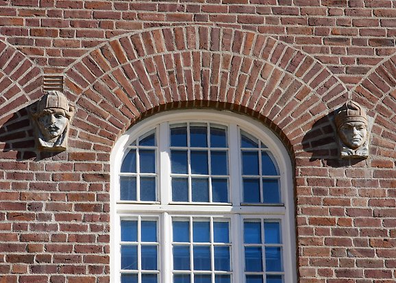 Detaljbild på stenskulptur på tegelfasad.