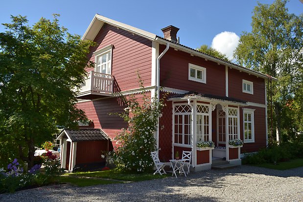 Björken 1, Villa med röd liggande panel och punschveranda med små fönster.