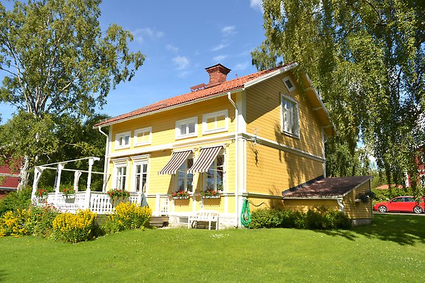 Björken 7. Villa i gul, liggande tapet och vita fönster.