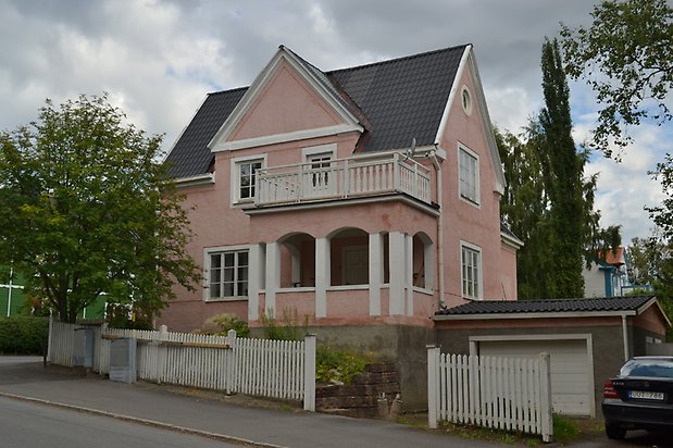 Laken 1, Villa i rosa puts med vita fönster och vita pelare som håller upp en balkong.