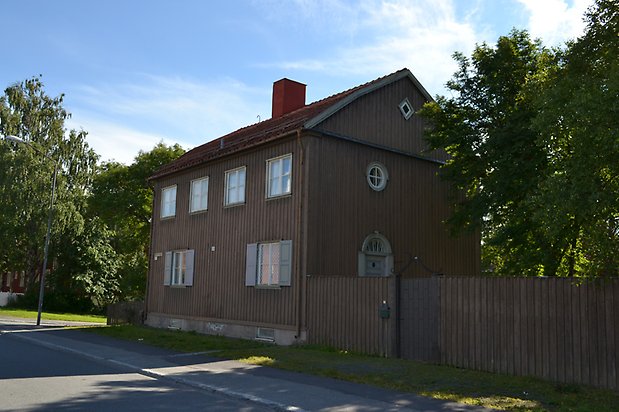 Siken 2. Villa i svart träpanel och vita fönster med spröjs och grå fönsterluckor.