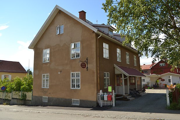 Siken 6. Hus i tre våningar, beige puts och vita fönster med spröjs.