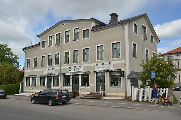 Solrosen 7. Flerbostadshus i tre våningar med beige puts och detaljer i vitt, gröna fönster med spröjs.