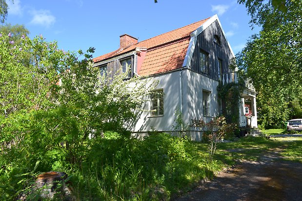 Öringen 5. Villa i två våningar med vit puts på nedre våningen och grå, träpanel på övervåningen, rött tegeltak.