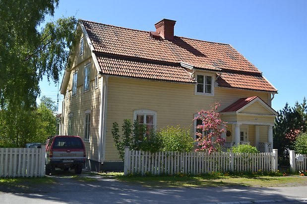 Öringen 6, Villa i gul, liggande panel, vita fönster med spröjs och rött tegeltak.