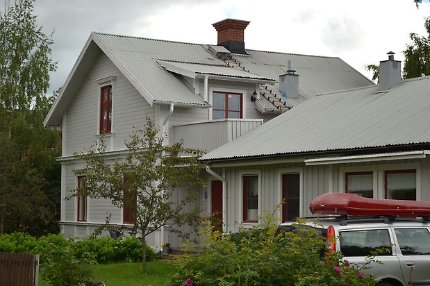 Blåklinten 8, Villa i grå, liggande panel och vita fönster med röda spröjs.