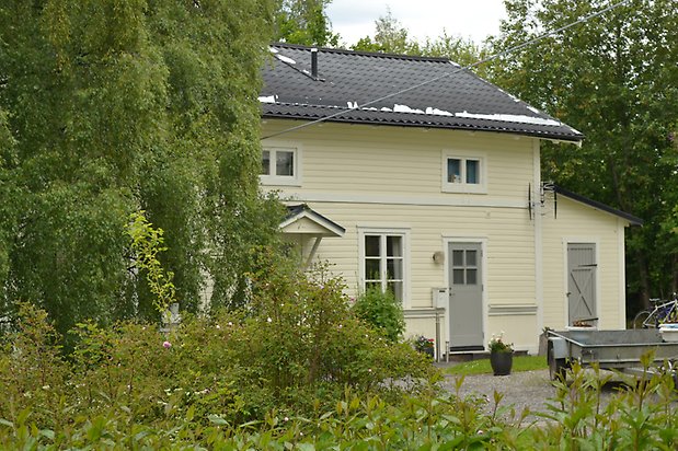 Nejlikan 7, Villa i ljusgul, liggande träpanel, vita fönster med spröjs och gråa dörrar.