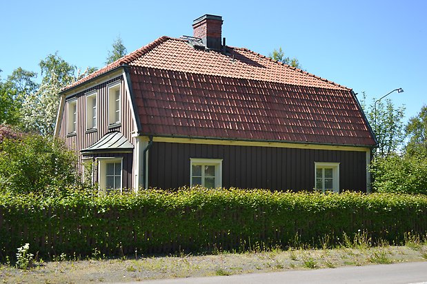 Öringen 2. Villa i brun träpanel med vita fönster i spröjs och ett buspråk.