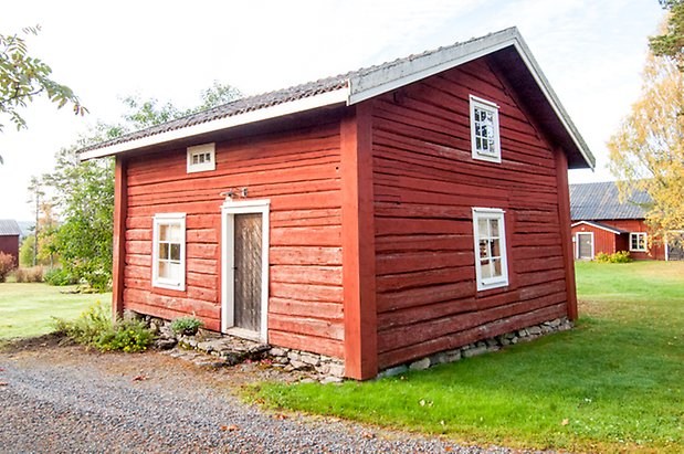 Timrat hus, målat i rött,  i två våningar med vita fönster med spröjs.