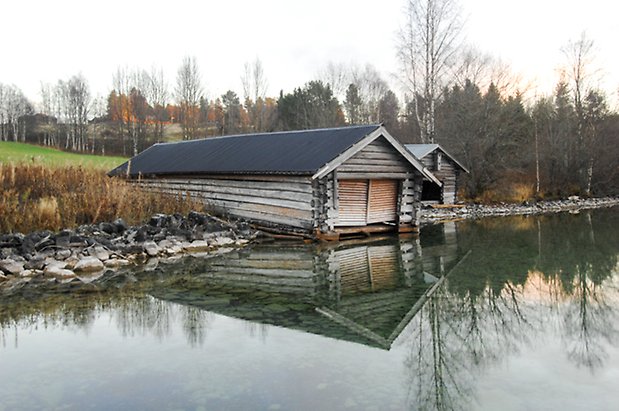 Timrat båthus vid vatten.