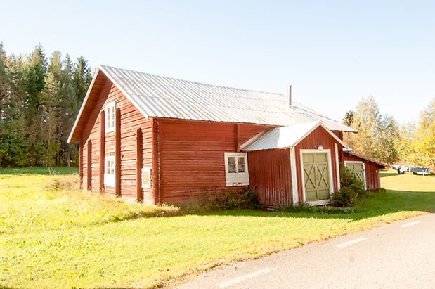 Timrad byggnad i två våningar med fönster med spröjs och gröna portar.