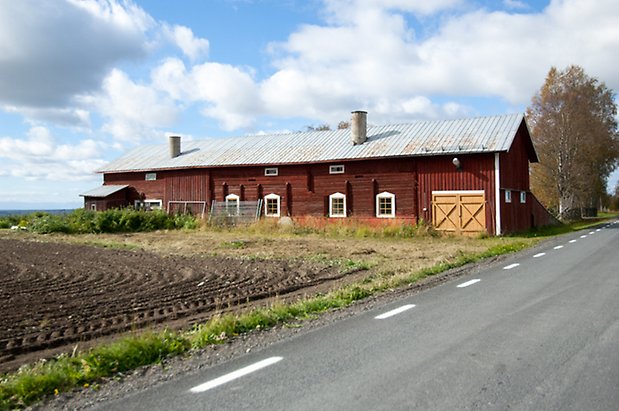 Timrad byggnad i rött i två våningar med fönster med gula spröjs och gula portar.