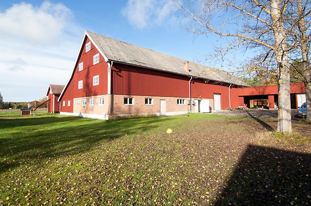 Byggnad i fyra våningar med undervåning i tegel och övre våningar i röd panel.