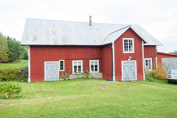 Röd byggnad i två våningar, med fönster med vita spröjs och gråa portar.