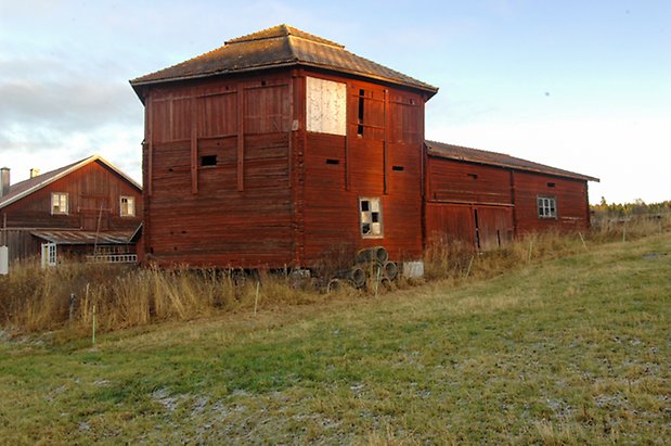 Timrad röd byggnad med ett fyrkantigt torn och fönster med spröjs.