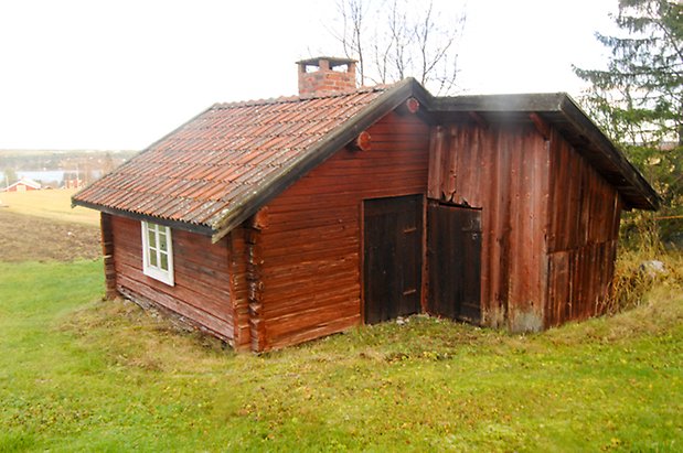 Timrad byggnad i rött med svarta dörrar och vita spröjs.