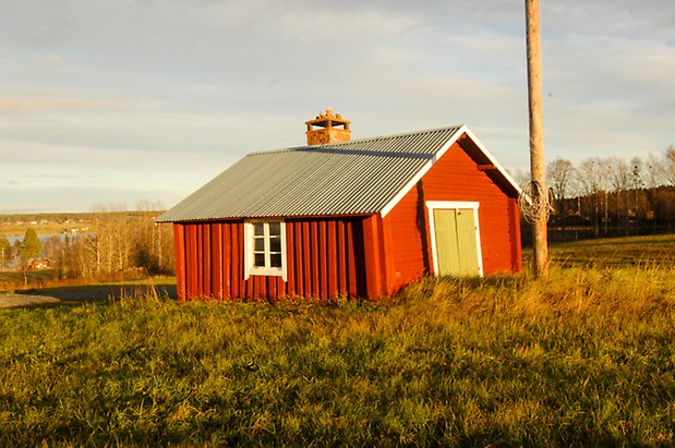 Byggnad med röd panel med grön port och fönster med vita spröjs.