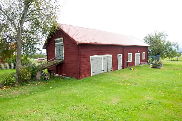 Timrad byggnad i två våningar med grå portar 