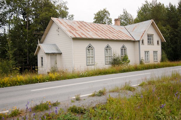 Hus i två våningar med grå fönster med vita spröjs.