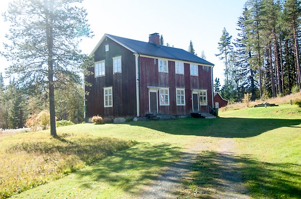 STort hus i två våningar med fönster med vita spröjs och bruna dörrar.