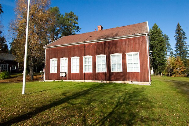 Stort hus i röd panel med fönster med vita spröjs.