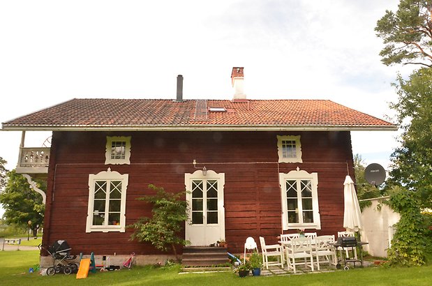 Byalaget 27 - Rött timrat hus med vita fönster med spröjs och snickarglädje.