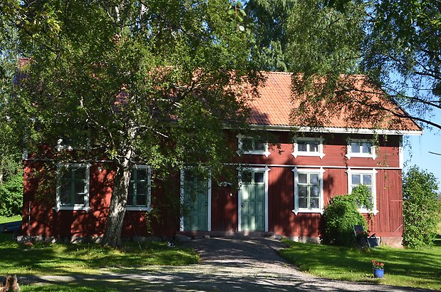 Löfstagården 1 - Röd gammal bryggstuga med gröna dörrar.