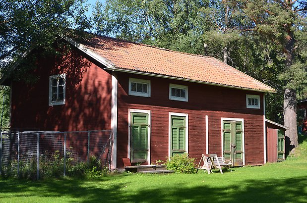 Löfstagården 1 - Gammal röd ladugård med gröna dörrar.