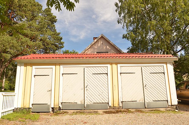 Igelkotten 3 - Uthus i gul träpanel och gråa dörrar.