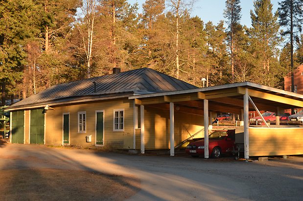 Karlslund 2:1 - Byggnad med gul träpanel och gröna dörrar och carport.