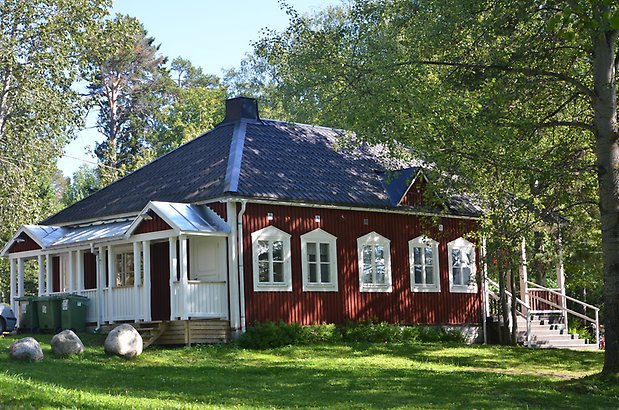 Karlslund 2:5 - Rött hus med vita knutar och veranda med vitt staket.