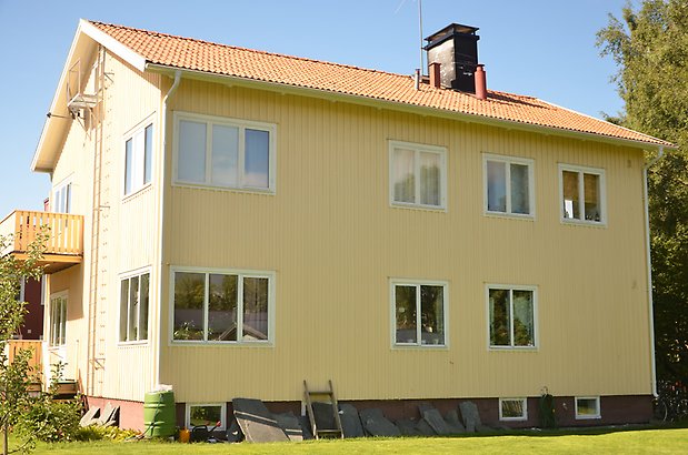 Mården 8 - Bostadshus med gul träpanel och vita fönster.