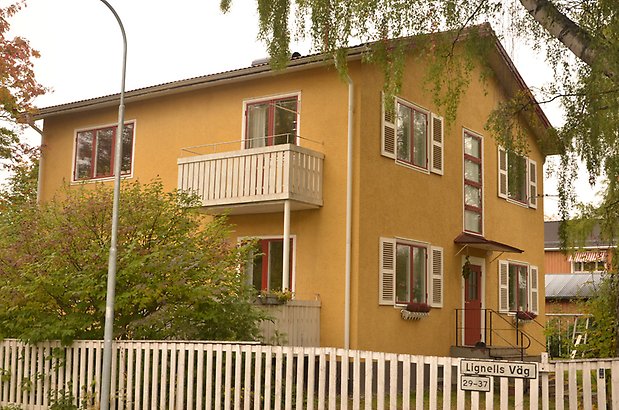 Renen 6 - Bostadshus i gul puts med röda fönster och vita fönsterluckor.