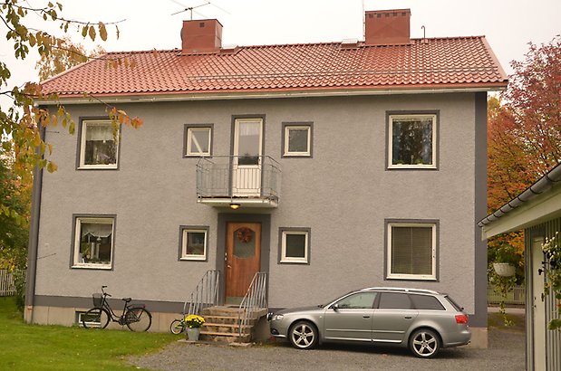 Renen 7 - Bostadshus i ljusgrå puts med mörkgrå knutar och rött tegeltak.