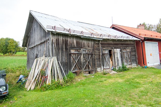 Boda 1:6. Byggnad i grånad träpanel med två dubbelportar.