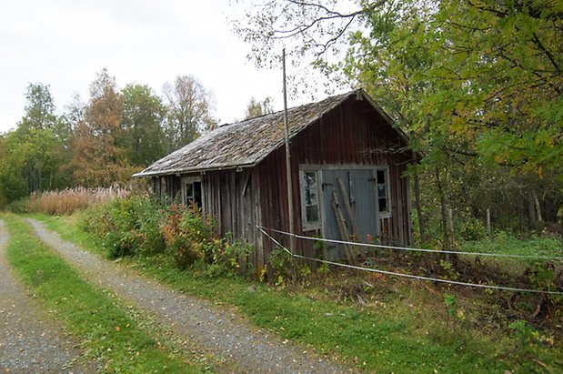 Boda 1:8. Litet hus i grånad panel med fönster med spröjs och blå dubbelport.