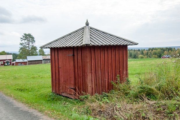 Boda 1:15. Liten, fyrkantig byggnad i röd panel med röd dörr.