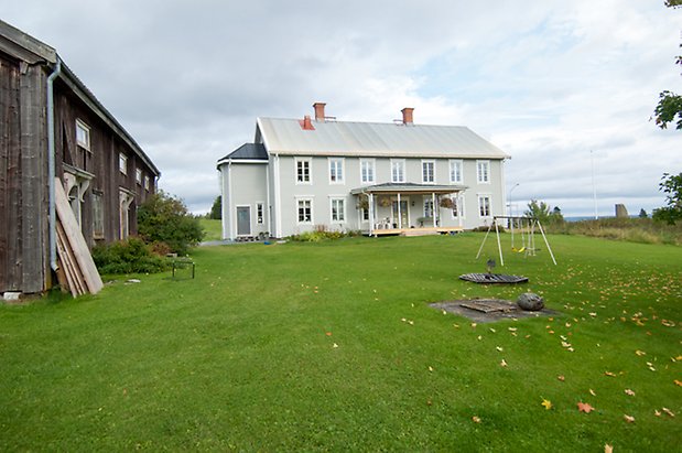 Boda 2:2. Stort ljusgrått hus med fönster med vita spröjs.