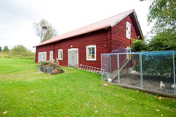 Boda 2:2. Timrad ladugård i rött med tre grå dubbelportar och fönster med spröjs.