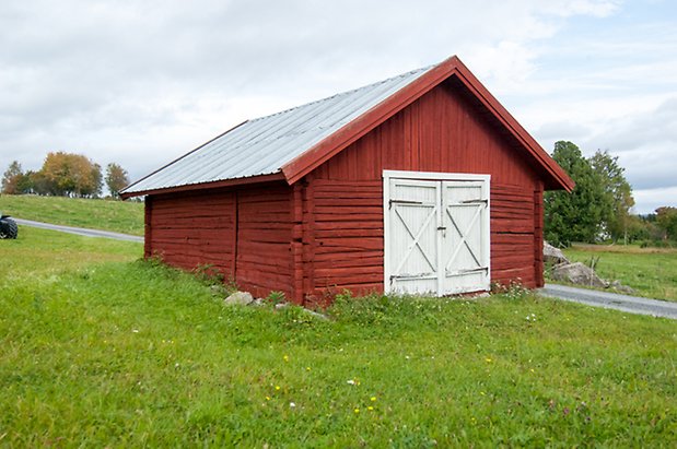 Boda 2:2. Timrad garagebyggnad i rött med vita dubbeldörrar.