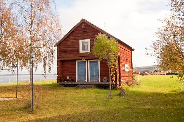 Brevåg 1:12. Timrad, rödmålad byggnad i två våningar, med blå dörrar och fönster med vita spröjs.