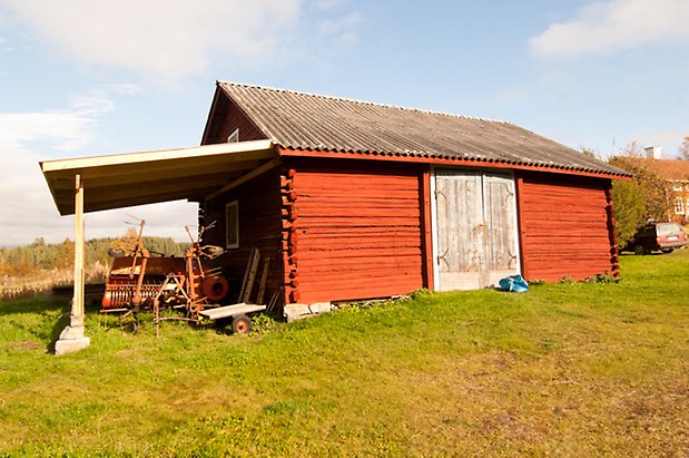 Brevåg 1:12. Timrad, rödmålad byggnad med grå dubbelportar och påbyggt skärmtak.