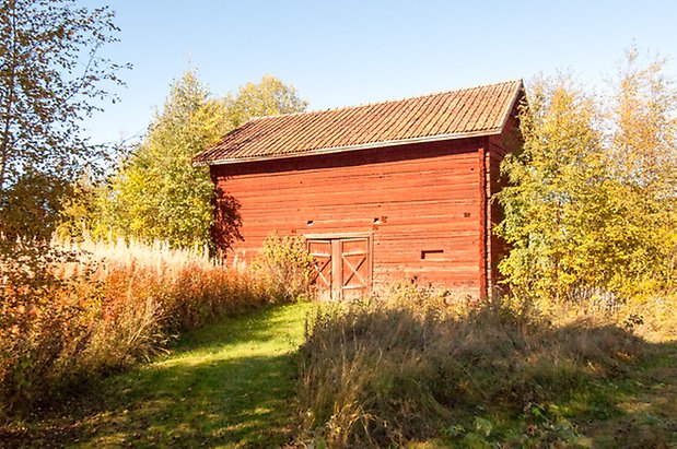 Fjäl 1:22. Timrad, rödmålad byggnad med röda dubbelportar.